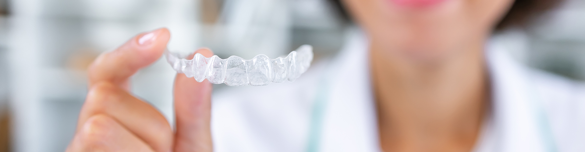 smiling woman holding clear aligner